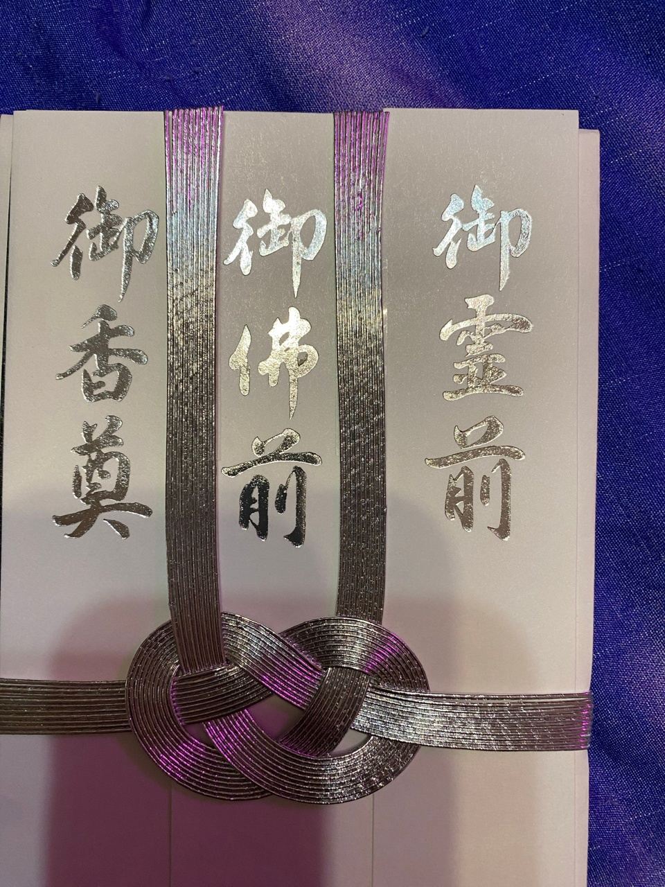 Это оказалась открытка - "香典袋 (kōdenfukuro) — конверт для денег, преподносимых семье усопшего на похоронах. Если правильно понимаю, то надписи находятся на трёх отдельных полосках, и приглашённый на похороны должен выбрать одно из этих трёх слов — 御香奠, 御佛前, 御霊前 — в зависимости от того, по какому обряду проходит церемония, и оставить на лицевой стороне полоску с подходящим". Такую открытку я подарила сестре просто так. Она хранит её как сувенир. 