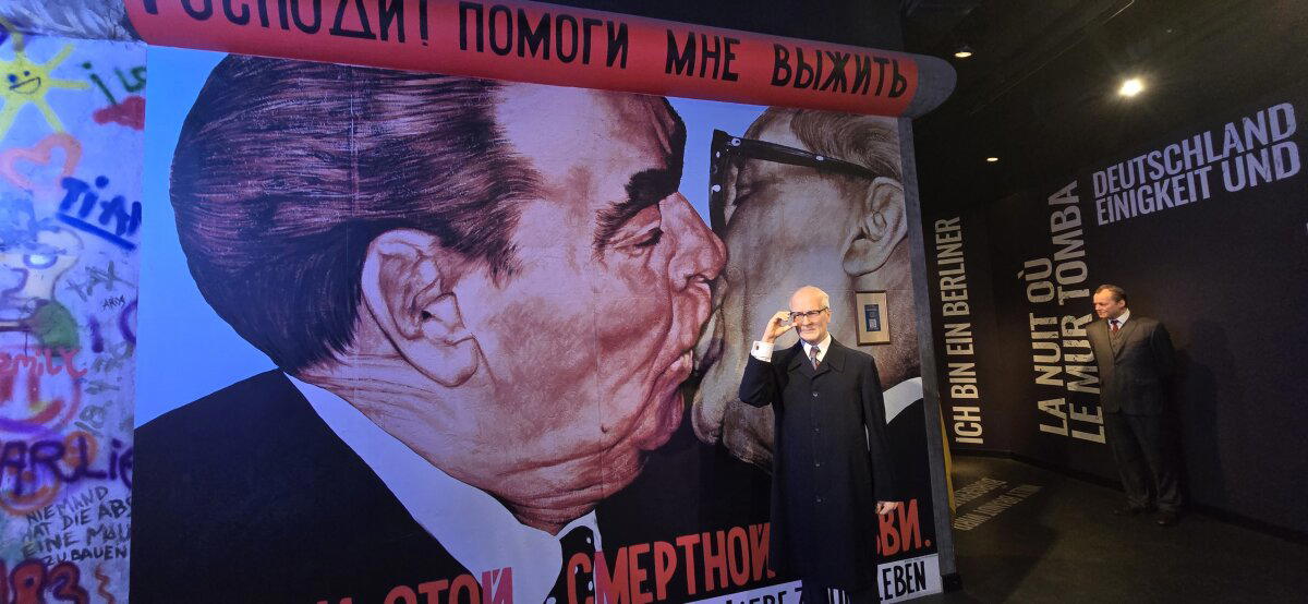 Делает это он на фоне знаменитой картины, где он взасос целуется с дорогим Леонидом Ильичом, которая называется "Господи! Помоги мне выжить среди этой смертной любви."