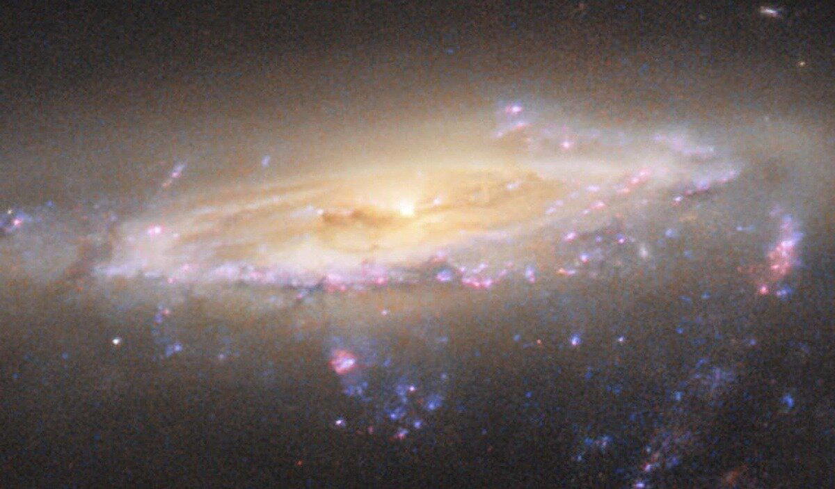 Яркие розовые области — очаги звездообразования. Но процесс идет на спад и в будущем прекратится полностью из-за нехватки ресурсов / © NASA/ESA