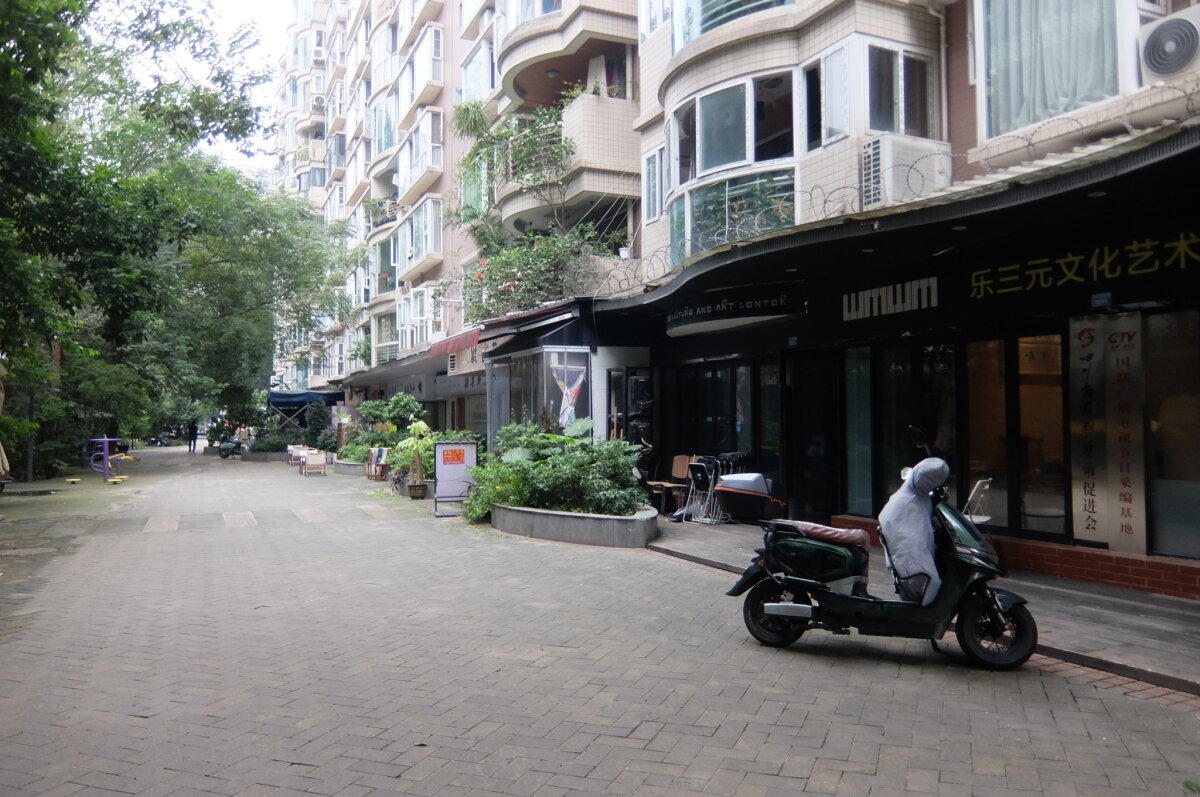 Почти двор - слева бетонный забор. Если внимательно приглядеться, то видно колючую проволоку на крышах магазинов вдоль дома.