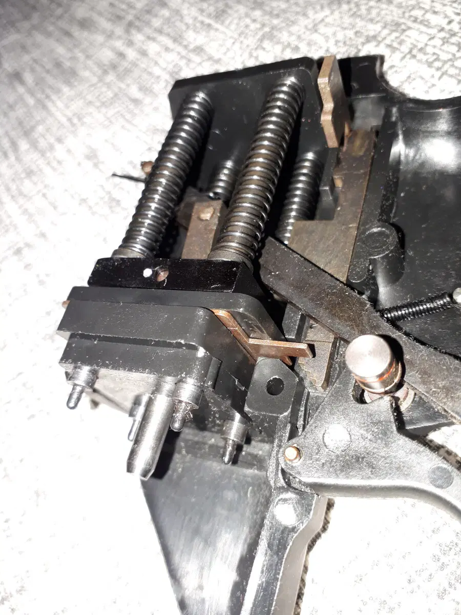 Рамка не медная. Просто воронение кафно. Интересно другое. Эта рамка удерживает бойки на взводе и освобождает их по одному. По сути рамка это пластина с вырезами под бойки, но на разной высоте. На шептале есть "лесенка" (под язычком "медной" рамки). Лесенка позволяет шепталу отпускать бойки по одному (молчи сопляк-ляк-ляк-ляк!) или отпустить все разом, если шептало смещено переключателем (скибирибири до ро то!).  