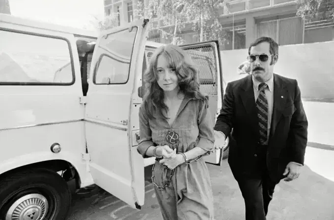 Агент спецслужб сопровождает Линнет на суд по делу о покушении на президента