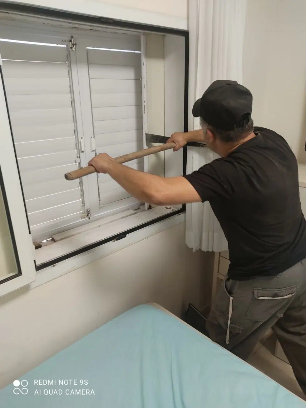 Мужчина задвигает бронированные ставни.